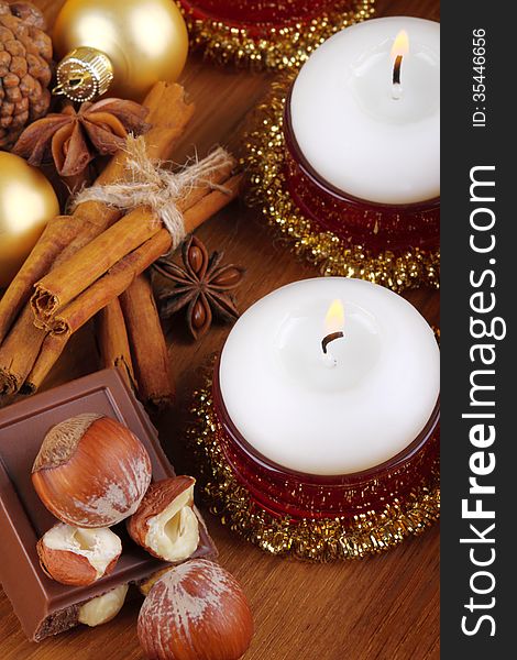 Christmas candles with cinnamon, chocolate and hazelnuts on wood. Christmas candles with cinnamon, chocolate and hazelnuts on wood