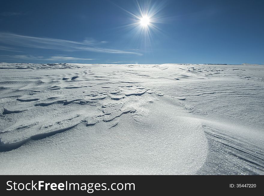 Winter alpine scenery with snow dunes and frozen snow in the Alps