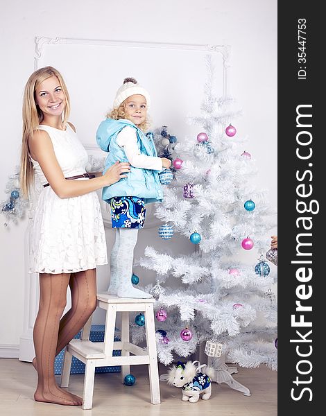 Little girl and her mother decorate Christmas tree. Little girl and her mother decorate Christmas tree