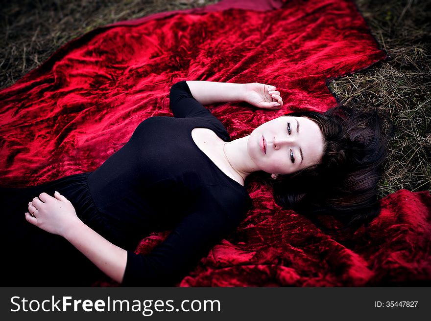 Pale Woman In Black Dress Lying On Red Carpet