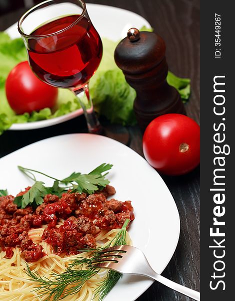 Closeup of plate with pasta near red wine and vegetables. Closeup of plate with pasta near red wine and vegetables