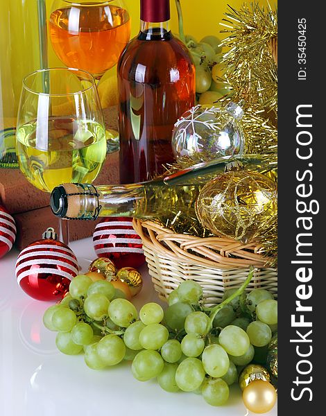 Bottles of wine with grapes and Christmas decorations on a white top and yellow cloth background