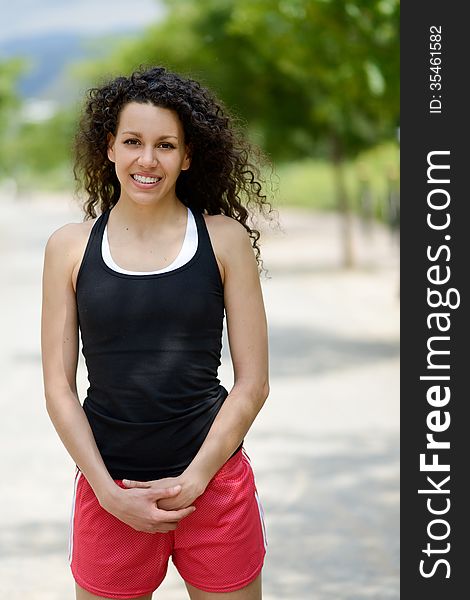 Young cheerful smiling woman in sports wear in urban background