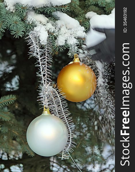 Golden and silver christmas balls on the fir-tree in snow. Golden and silver christmas balls on the fir-tree in snow