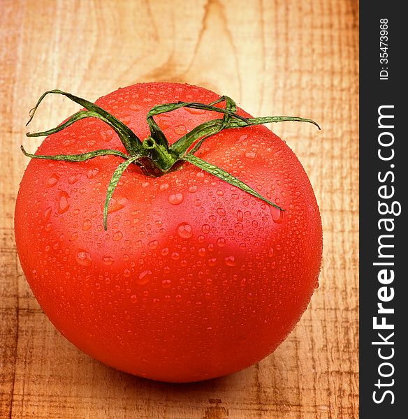 Big Ripe Tomato with Water Drops closeup on Rustic Wooden background