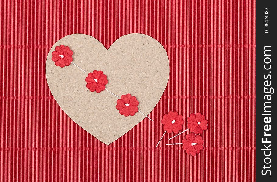 Cardboard heart with paper flowers on red background. Handcraft.