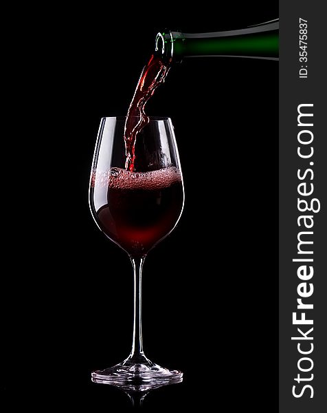 Red wine being poured into a glass on a black background