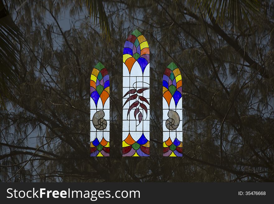 Stained glass window reflected against background of Casuarina trees. Stained glass window reflected against background of Casuarina trees