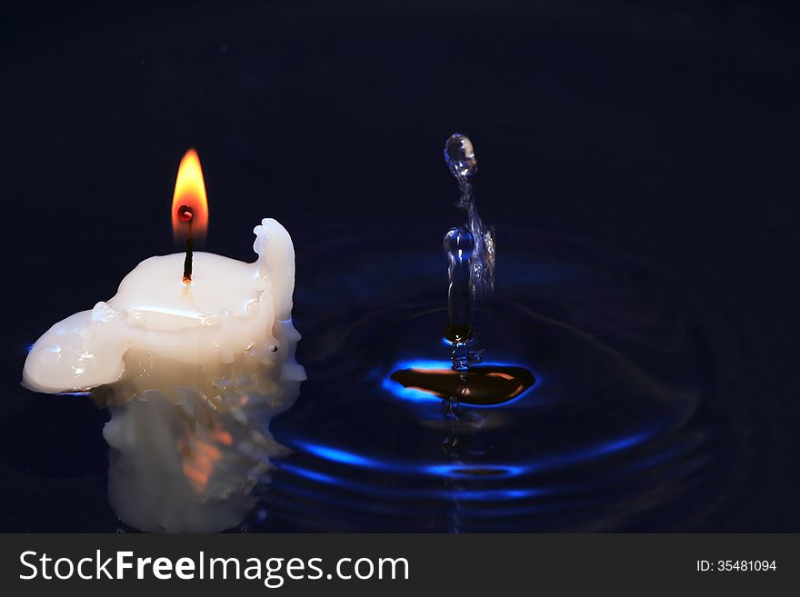Lighting candle on dark splashing water surface. Lighting candle on dark splashing water surface