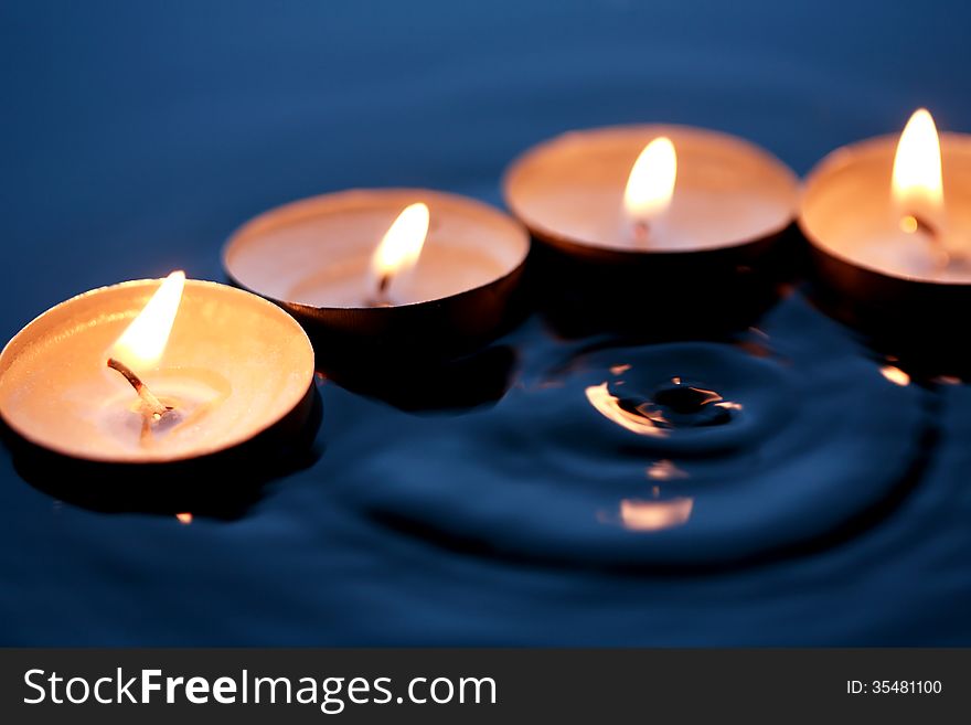 Few lighting candles on dark splashing water surface. Few lighting candles on dark splashing water surface