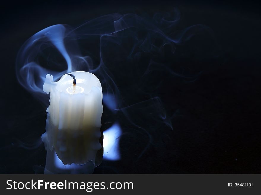 Extinguished candle with smoke on dark background