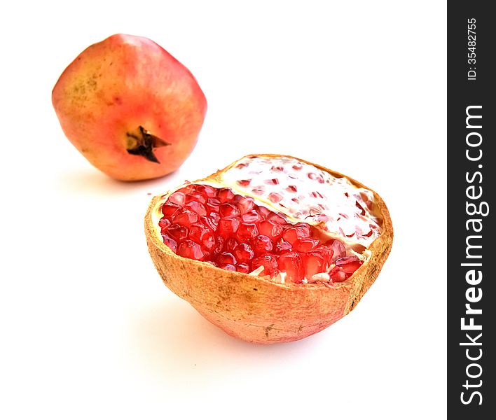 An open pomegranate fruit with a blurred full fruit in the background. An open pomegranate fruit with a blurred full fruit in the background