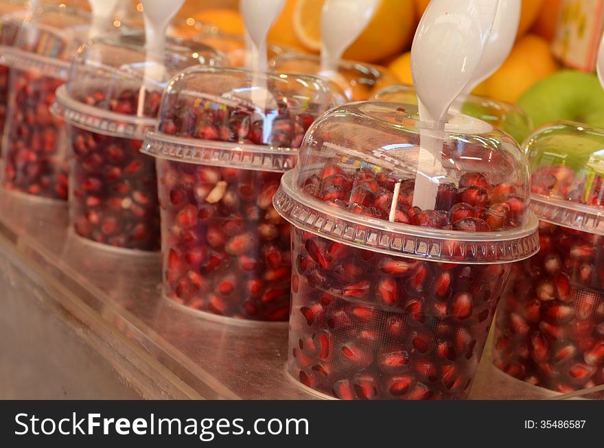 Grains of pomegranate in glass at market stand