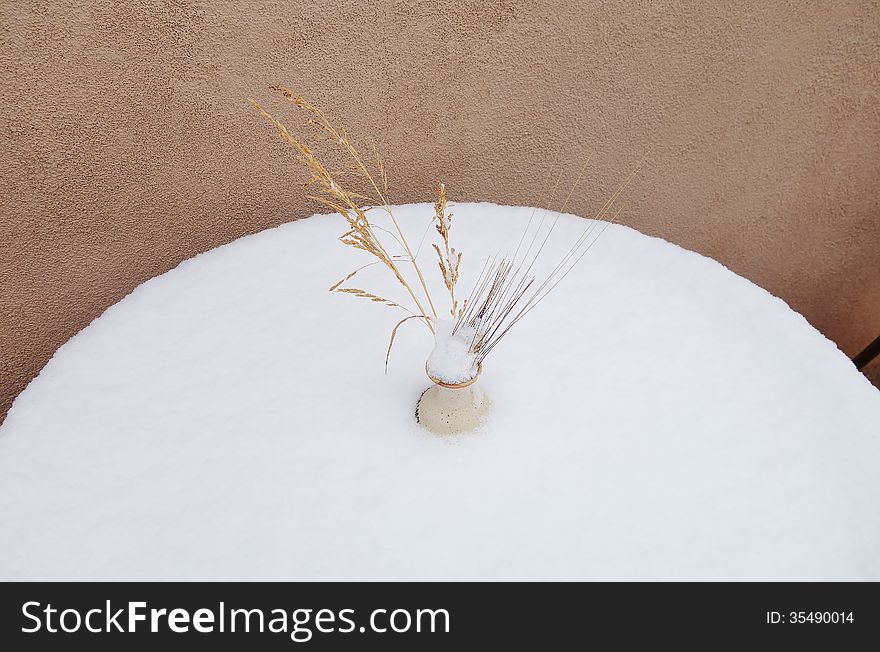 A picture of a dry flower bouquet on a patio table that got snowed on. A picture of a dry flower bouquet on a patio table that got snowed on.