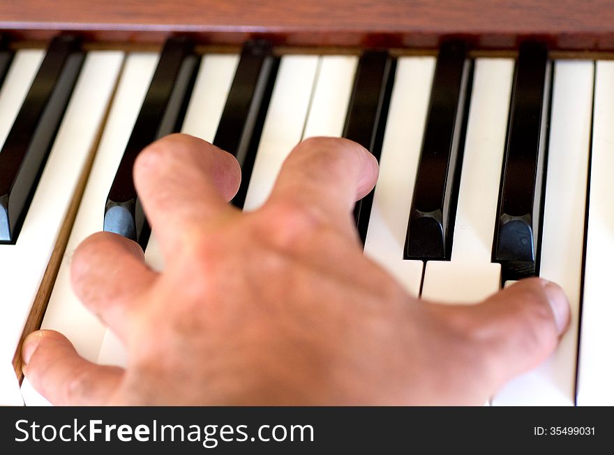 Piano player hand plays the piano.