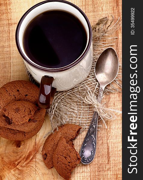 Arrangement of Rustic Cup of Black Tea with Chocolate Chip Cookies and Tea Spoon closeup on Wooden background. Top View. Arrangement of Rustic Cup of Black Tea with Chocolate Chip Cookies and Tea Spoon closeup on Wooden background. Top View