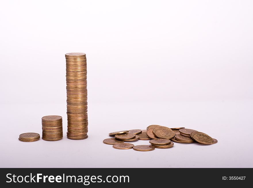 Piles of yellow coins against white background. Last one collapsed. Piles of yellow coins against white background. Last one collapsed.