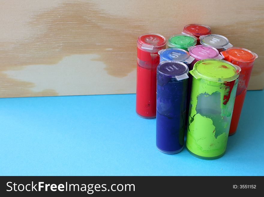 Paint bottles against a wooden box on a blue sheet. Paint bottles against a wooden box on a blue sheet