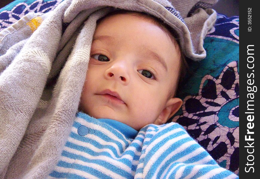 Three month old baby with a light blanket around his head. Three month old baby with a light blanket around his head