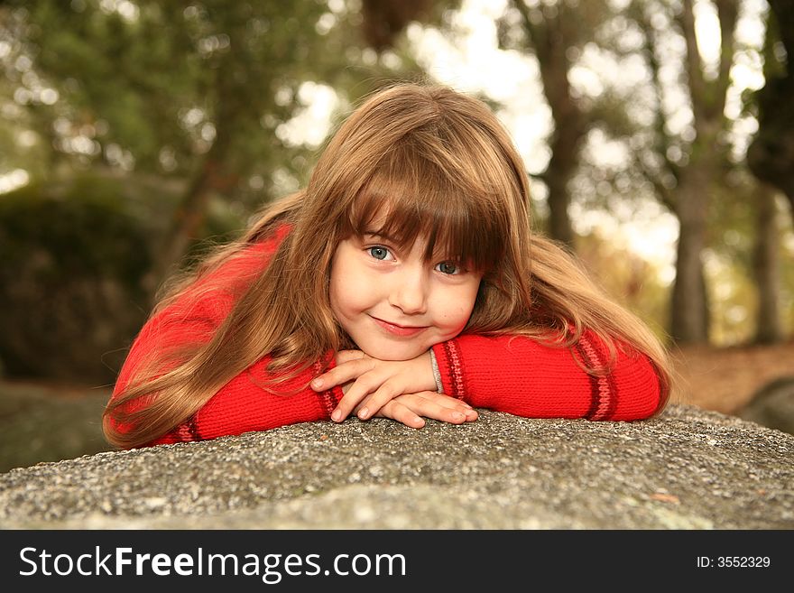 Girl Holding Her Face Smiling Outdoors on a Rock