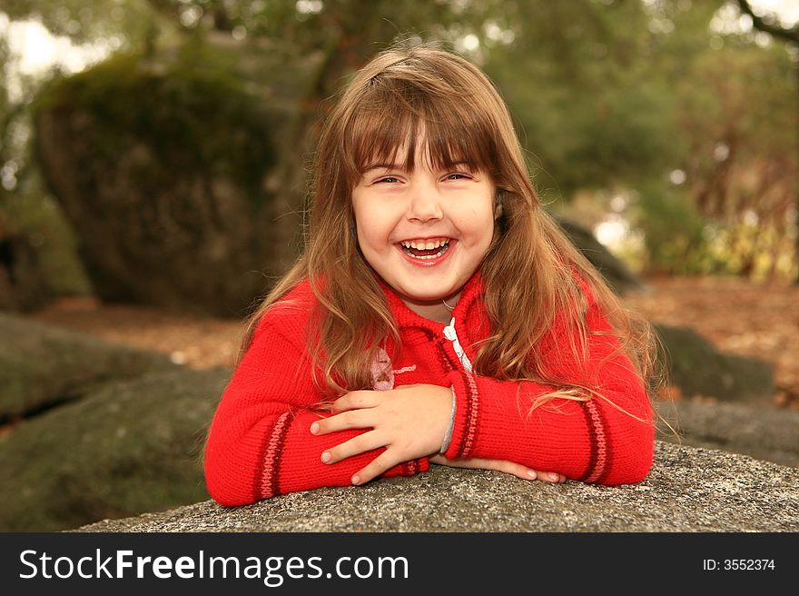 Girl Holding Her Face Smiling Outdoors on a Rock