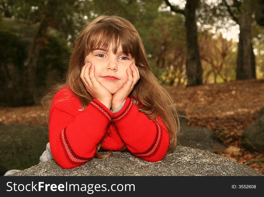 Young Girl Outdoors on a Rock Looking Bored. Young Girl Outdoors on a Rock Looking Bored