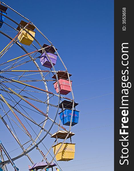 A colorful  ferris wheel at a fair against blue sky. A colorful  ferris wheel at a fair against blue sky