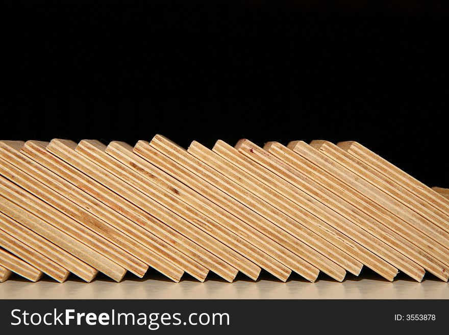 Fallen wooden domino blocks on black background.