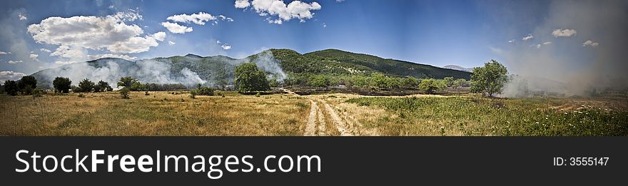 Panoramic view of a meadow with smoke from the dead fire