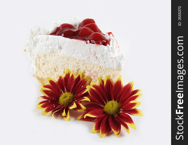 Piece of white cream cake and flowers isolated on white.