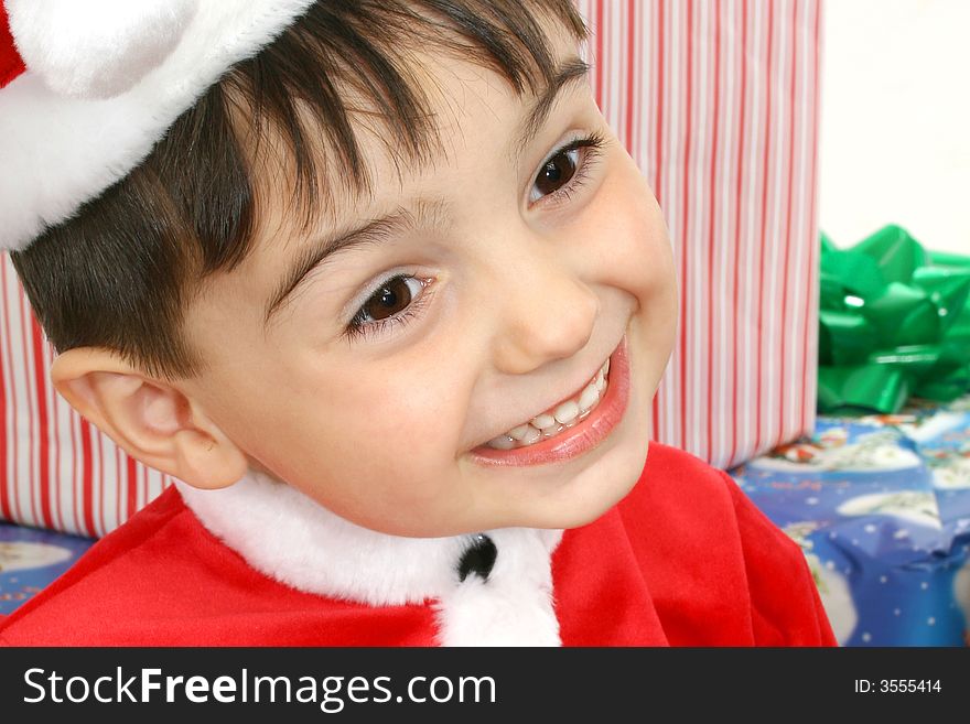 Toddler boy dressed in Santa suit sitting on packages.  Smiling. Toddler boy dressed in Santa suit sitting on packages.  Smiling.