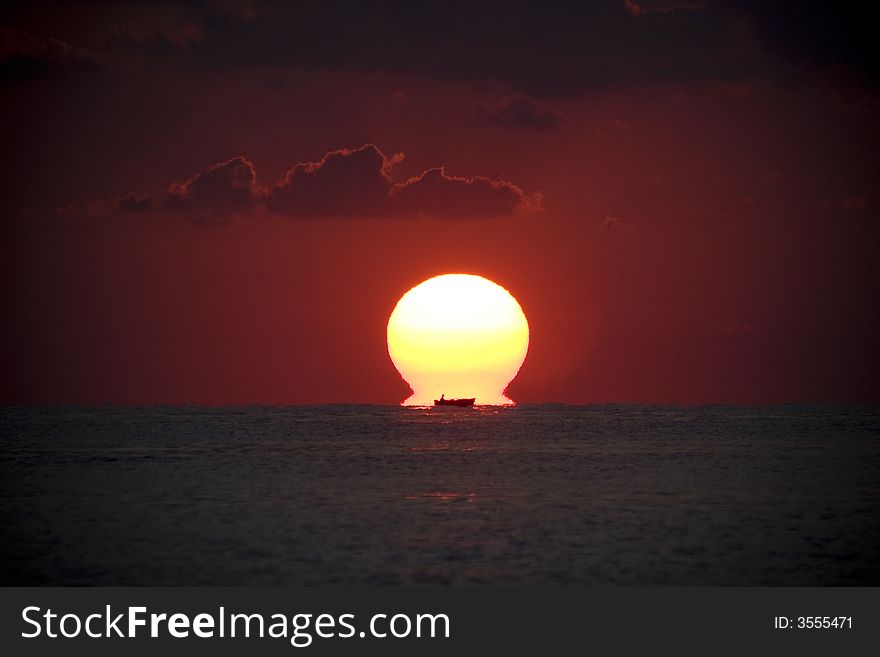 Sunrise with a silhouette of a boat in the sea