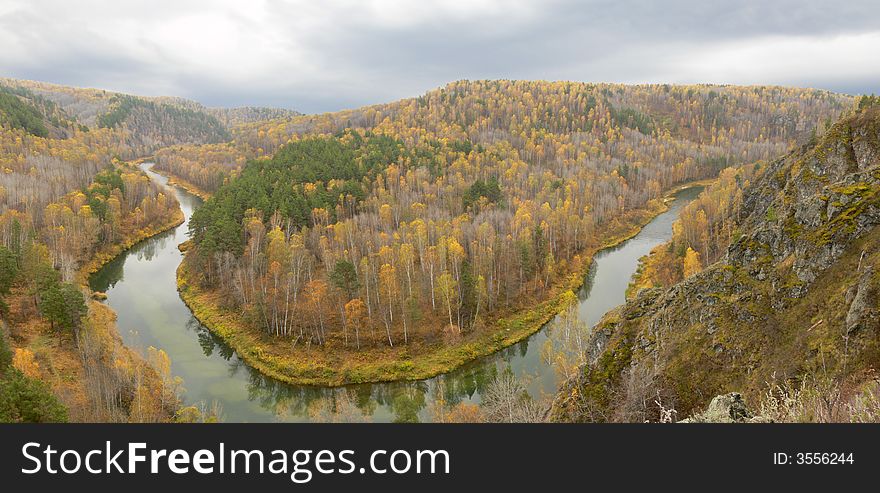 There is gray tranquil day and bright leaves. River makes a turning around hill. There is gray tranquil day and bright leaves. River makes a turning around hill.