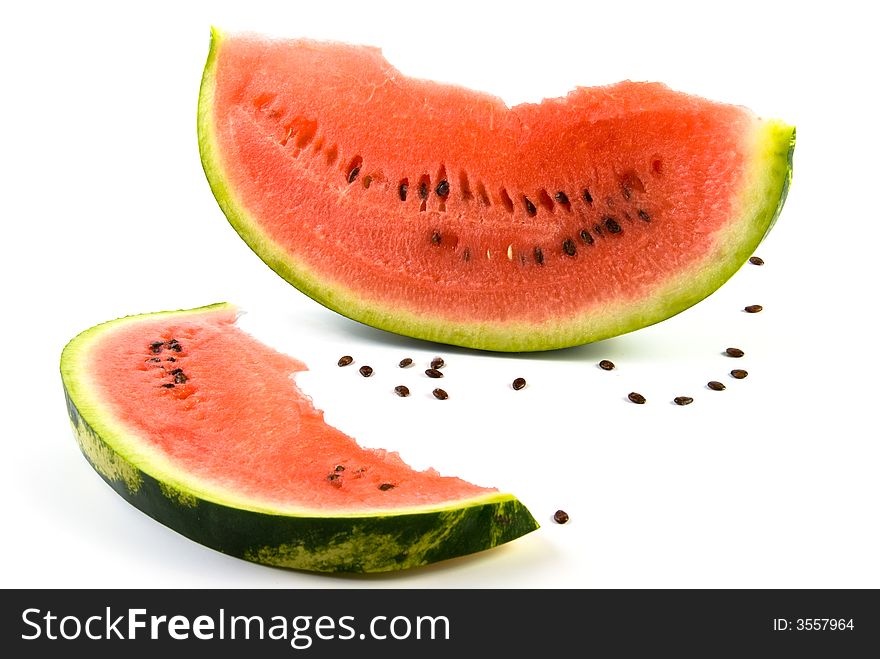 Two slices of ripe watermelon with scattered seeds over white background