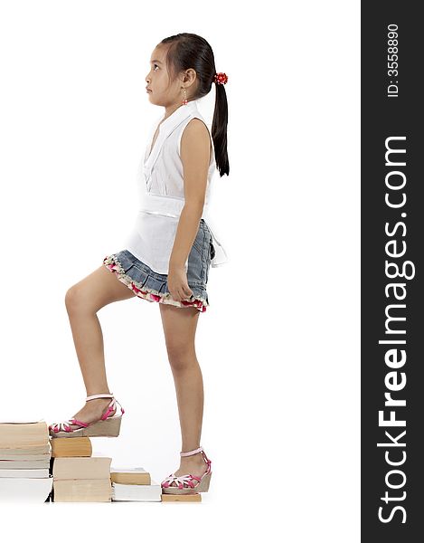 A girl climbing up by stepping on book stacks. A girl climbing up by stepping on book stacks