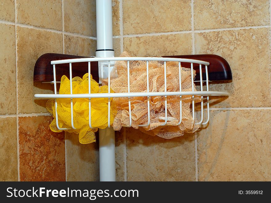 Two bath sponges in a white shower caddy rack