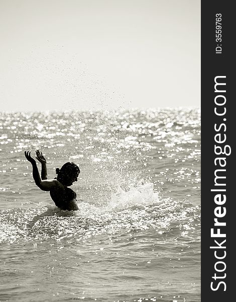 Silhouette of a wet young woman in a waving sea splashing the water, vertical. Silhouette of a wet young woman in a waving sea splashing the water, vertical