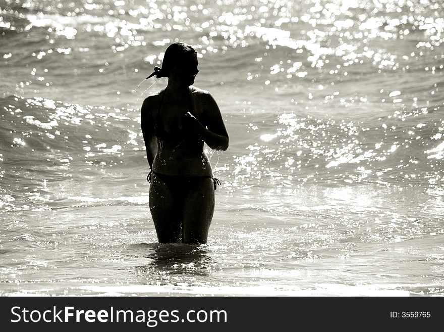 Silhouette of a wet young woman in a waving sea. Silhouette of a wet young woman in a waving sea