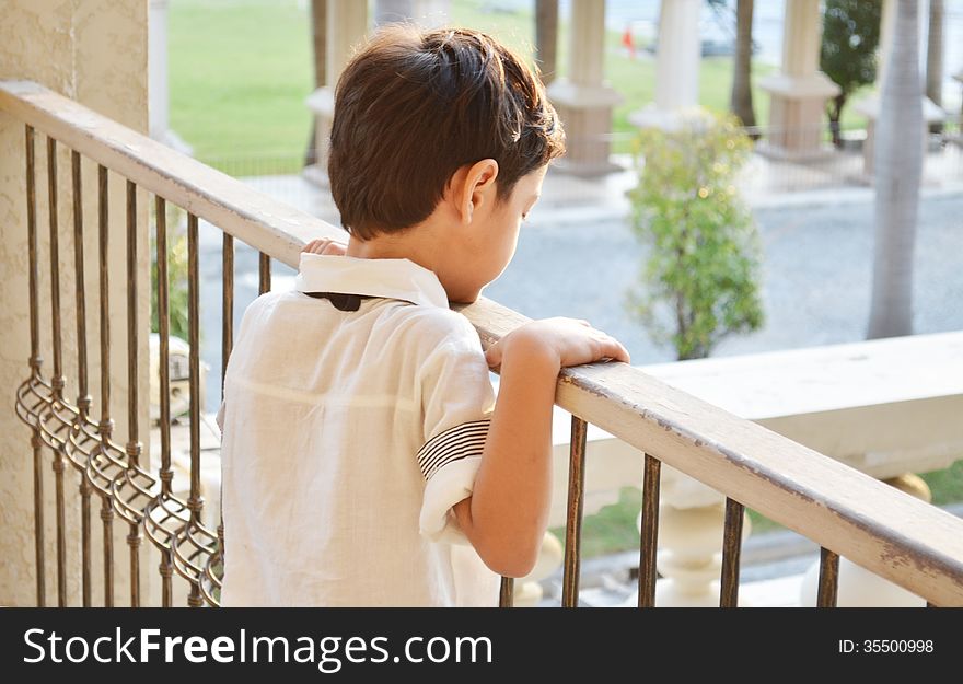 Little boy standing alone at balcony rimlight