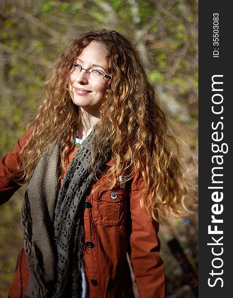 Smiling Woman With Glasses And Blonde Curly Hair On Sunny Forest Background