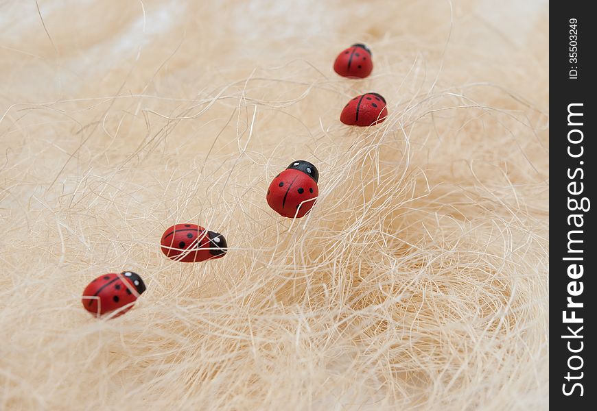Five artificial ladybirds in a cue on a straw background