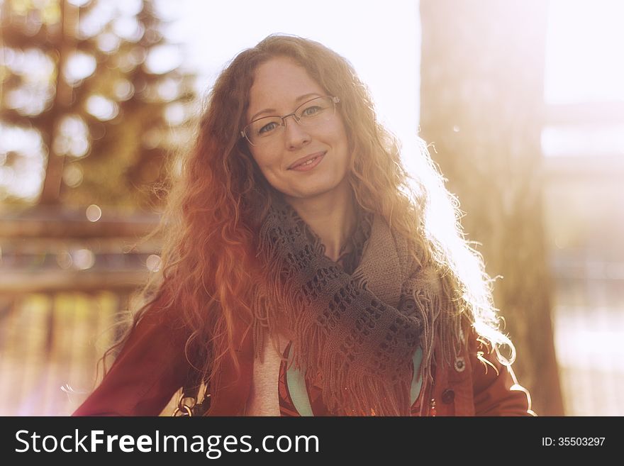 Happy woman with glasses and curly hair on sunny background