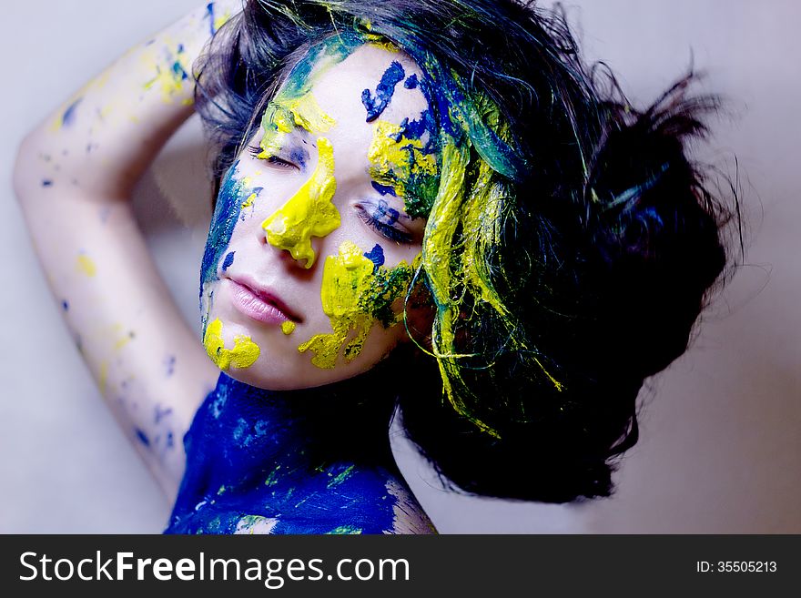 Beauty/fashion portrait of woman painted blue and yellow on black background