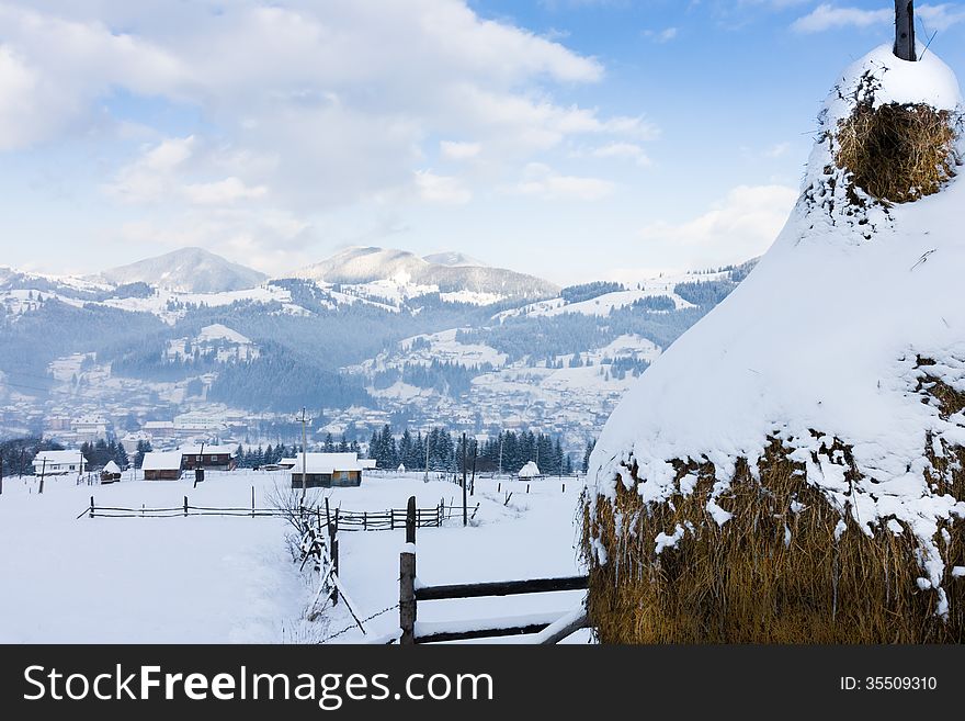 Snowy Haystack On A Background Of A Village In The Mountains