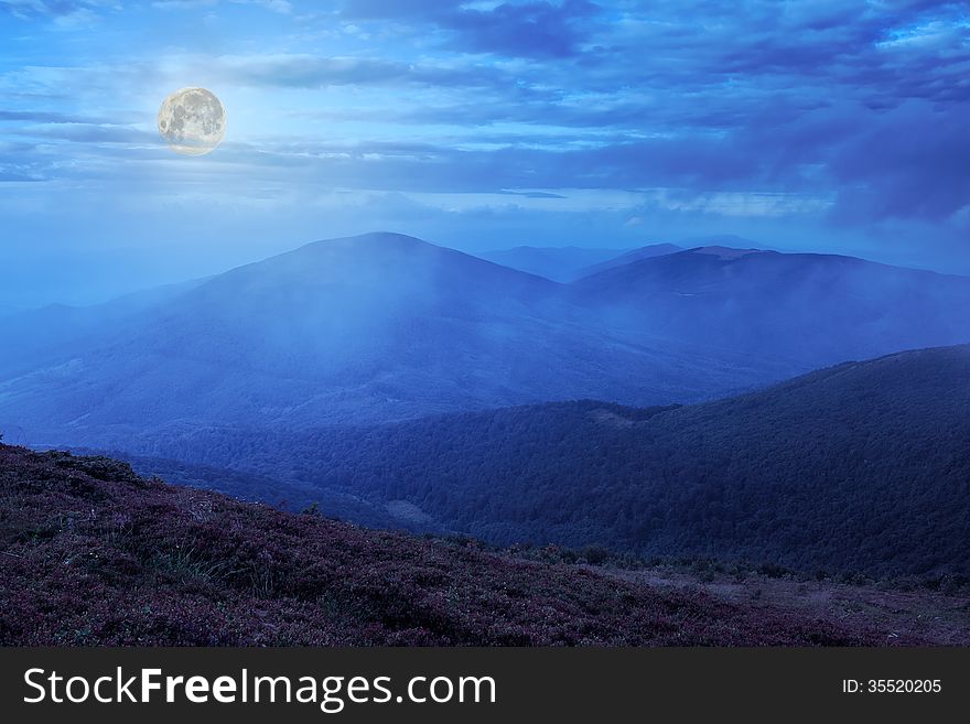 Mountain landscape. valley with stones on the hillside. forest on the mountain under the beam of light falls on a clearing at the top of the hill at midnight. Mountain landscape. valley with stones on the hillside. forest on the mountain under the beam of light falls on a clearing at the top of the hill at midnight