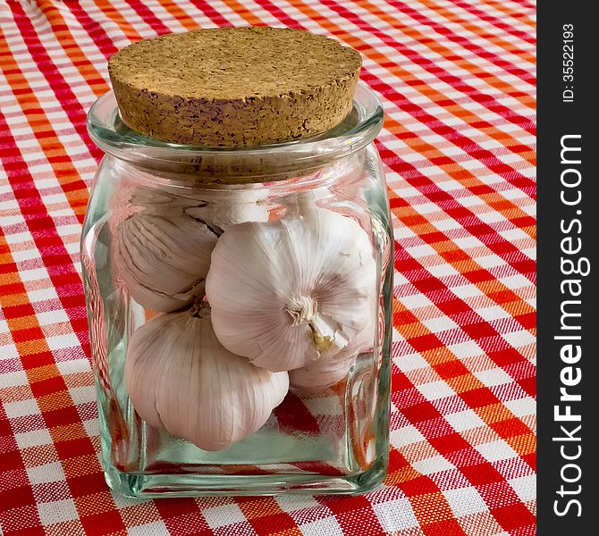 Garlic bulbs in glass jar on a checkered table-cloth
