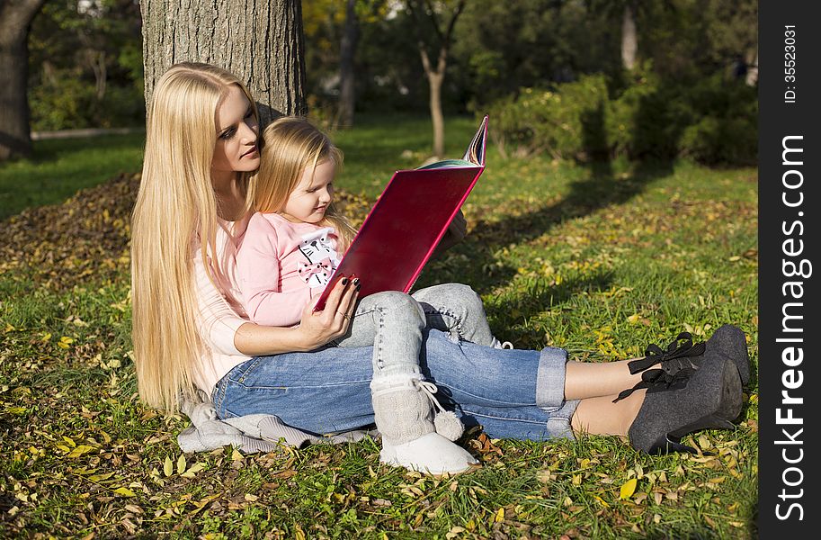 Beautiful mother reading book to her little daughter. Beautiful mother reading book to her little daughter