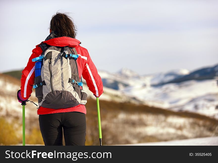 Woman hiking in winter mountains. Rear view of a female backpacker walking on a snow covered landscape. Woman hiking in winter mountains. Rear view of a female backpacker walking on a snow covered landscape.