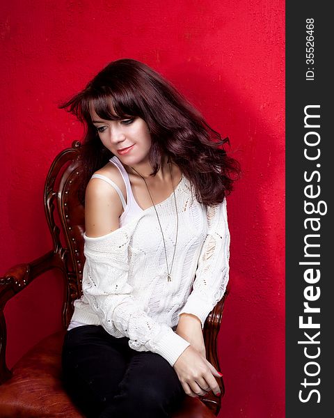 Beauty portrait of woman on vintage chair on red backround