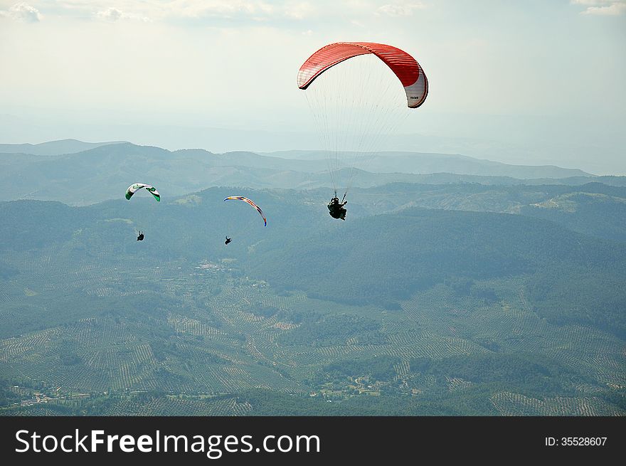 Three paragliders flying over the mountains in Spain